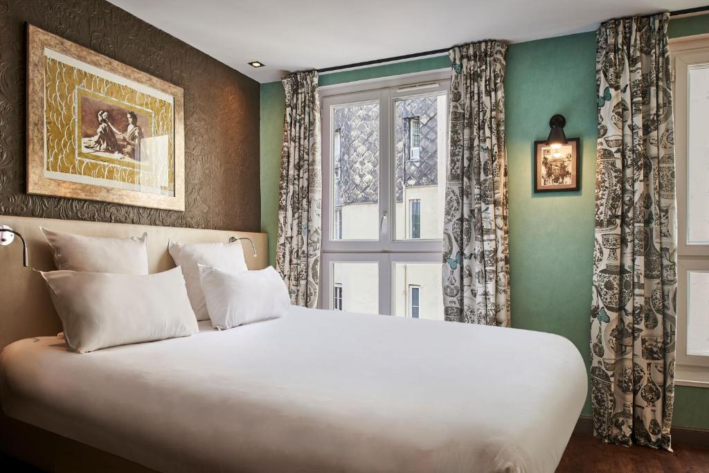 a bedroom with a large white bed and a window at R. Kipling by Happyculture in Paris