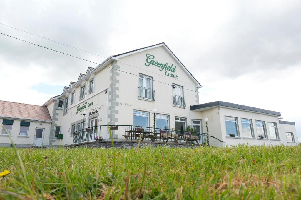 un bâtiment blanc avec bancs devant lui dans l'établissement Greenfield Lodge Hotel Bar & Bistro, à Headford