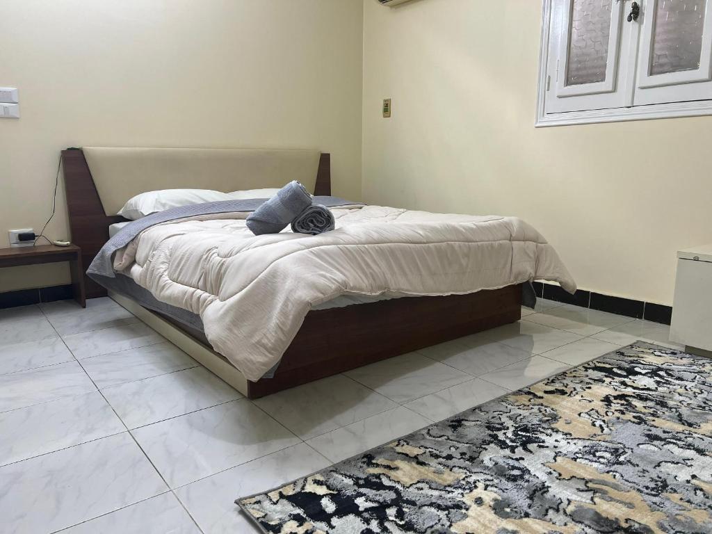een slaapkamer met een bed met 2 kussens en een tapijt bij Cairo's Heart Central Apartment in Masr El Gedida in Caïro