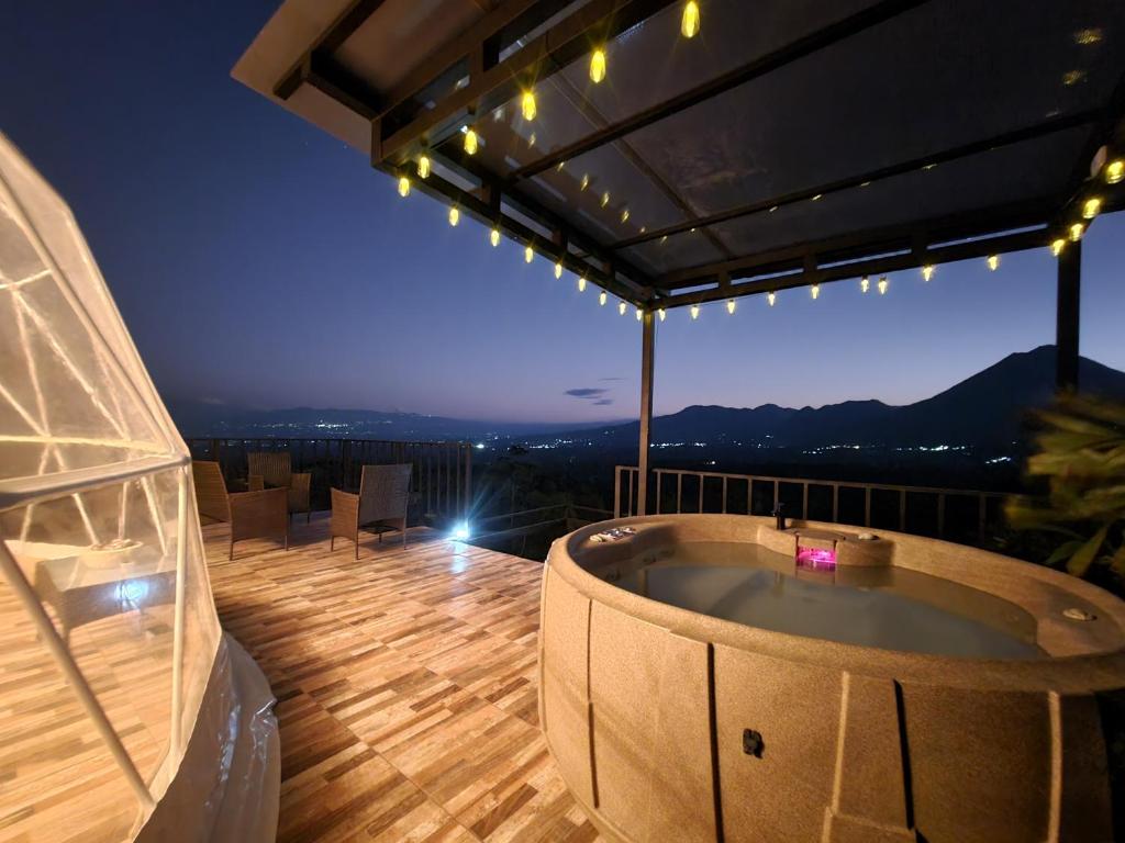 a hot tub on the balcony of a house at night at Volcano Views Glampings & Crystal House in Monterrey