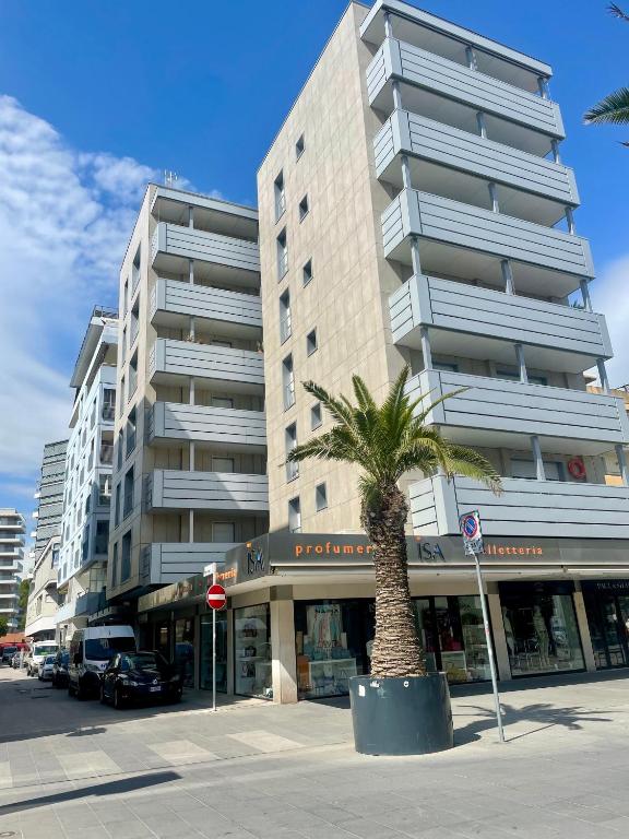 a palm tree in front of a tall building at Appartamento Lignano Sabbiadoro Centro in Lignano Sabbiadoro