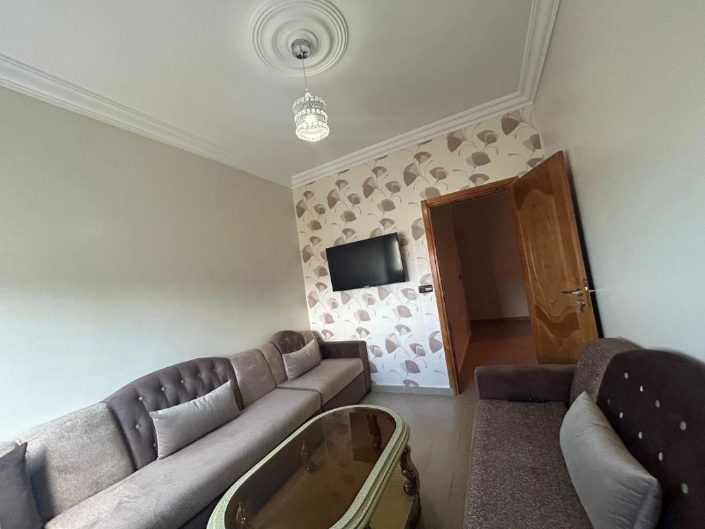 a living room with a couch and a tv at Appartement à Houma, proche Port Tanger Med in Dalia