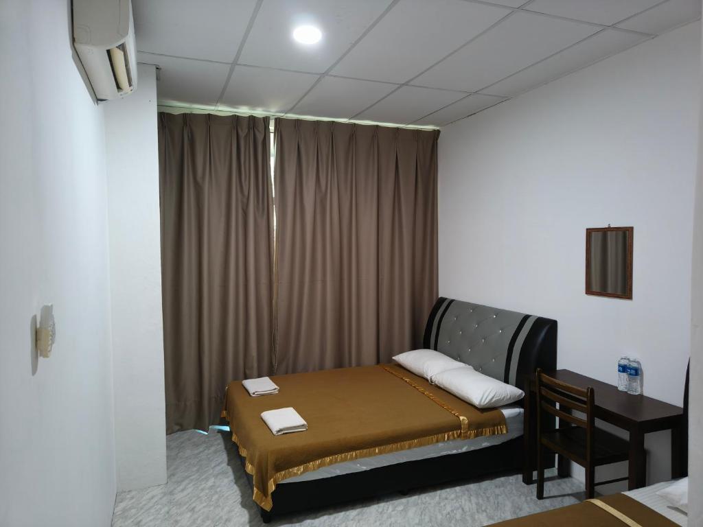 a small bedroom with a bed and a desk at NaVita Lodge in Tamparuli