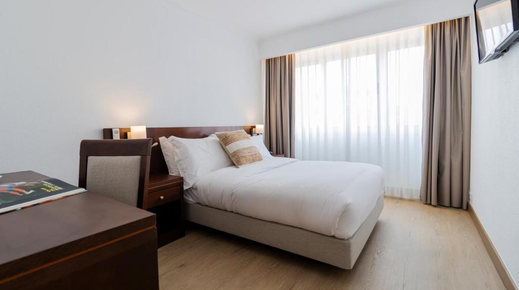 a hotel room with a bed and a window at Albergaria Quim Barreiros in Vila Praia de Âncora