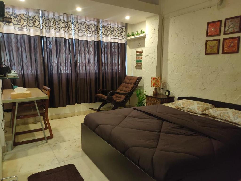 a bedroom with a bed and a desk and a chair at Anant Anurag Apartment - Juhu Beach in Mumbai