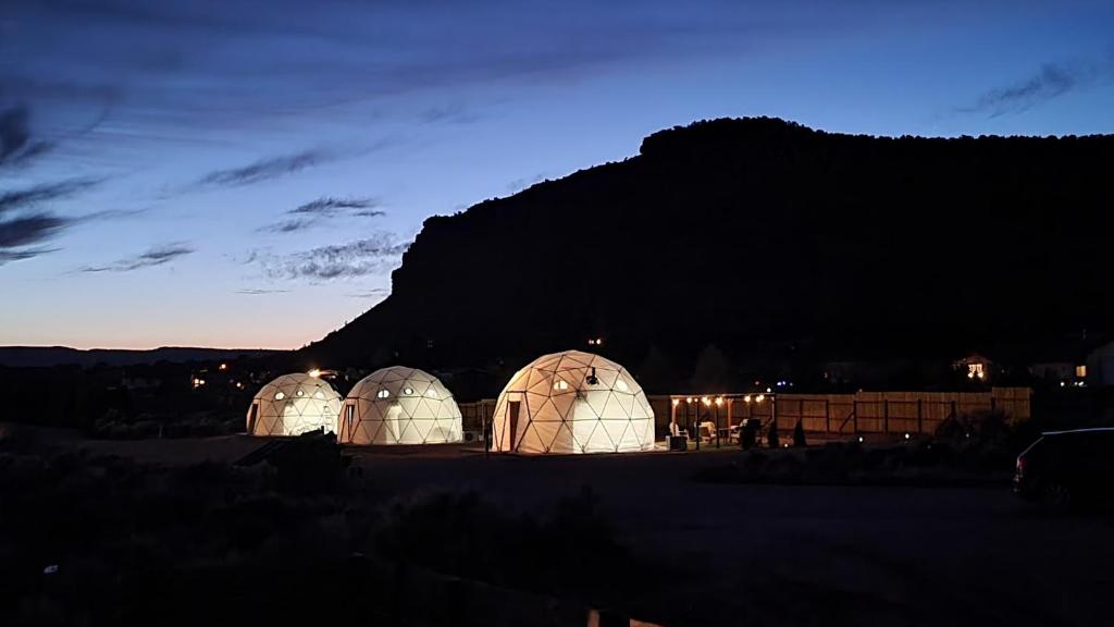 two domes in a field with a mountain in the background at White Camel in Kanab