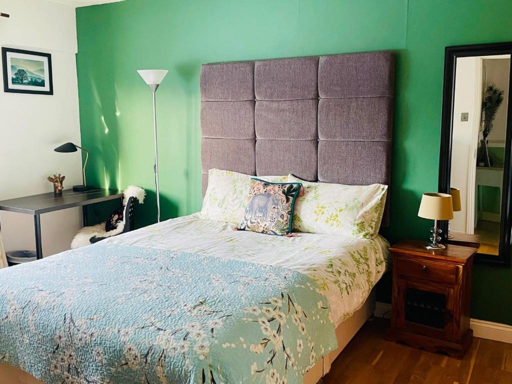 Un dormitorio con una cama grande y una pared verde en Modern and chic rooms with beautiful landscape views, en Sydenham