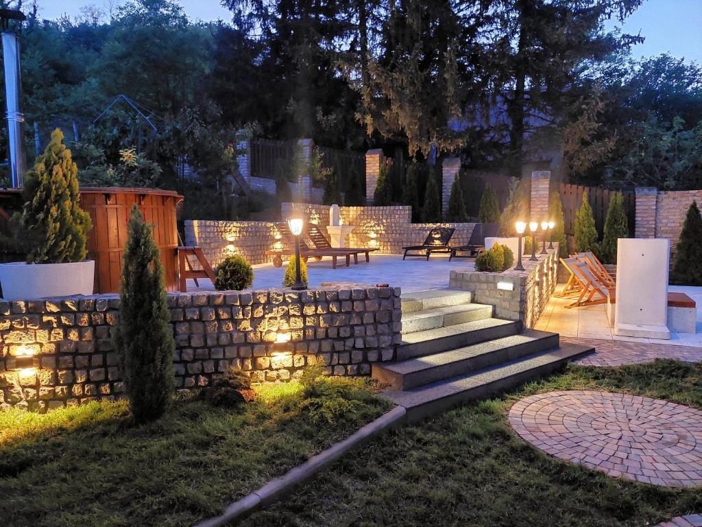 a backyard with a stone wall and stairs at night at Vila MP Banstol 4*- Brdež do, Fruška gora in Inđija