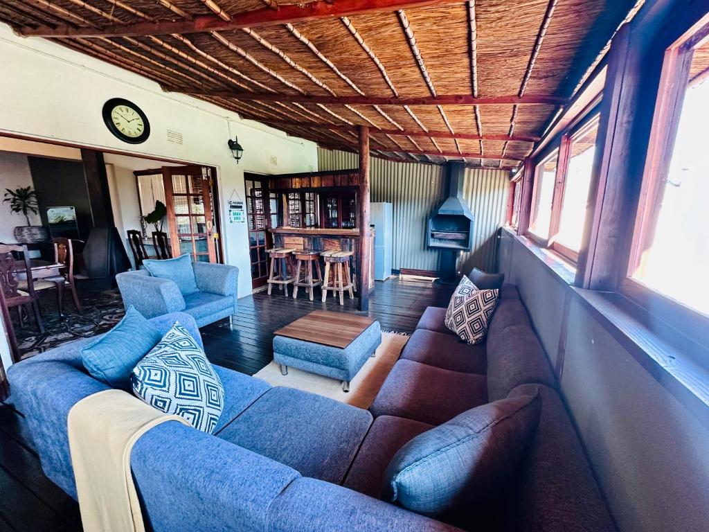 a living room with a couch and chairs and a clock at 49 on Main: A Spacious Self Catering Guesthouse in Sabie