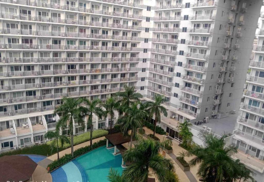 een uitzicht op een groot gebouw met een zwembad en palmbomen bij Shell Residences condotel Staycation in Manilla
