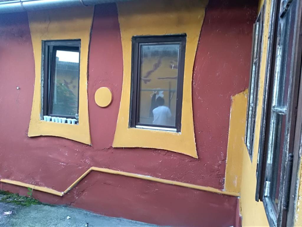 a person sitting in a window of a train at old house in Konjic
