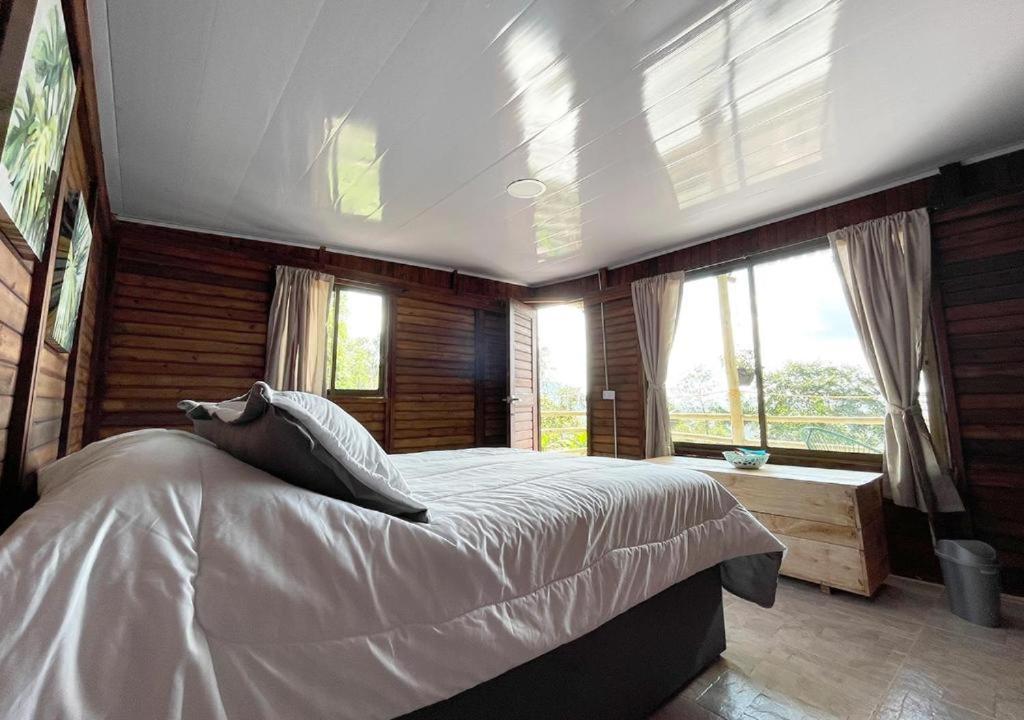 1 dormitorio con 1 cama grande en una habitación con ventanas en Yaque Glamping, en San Francisco