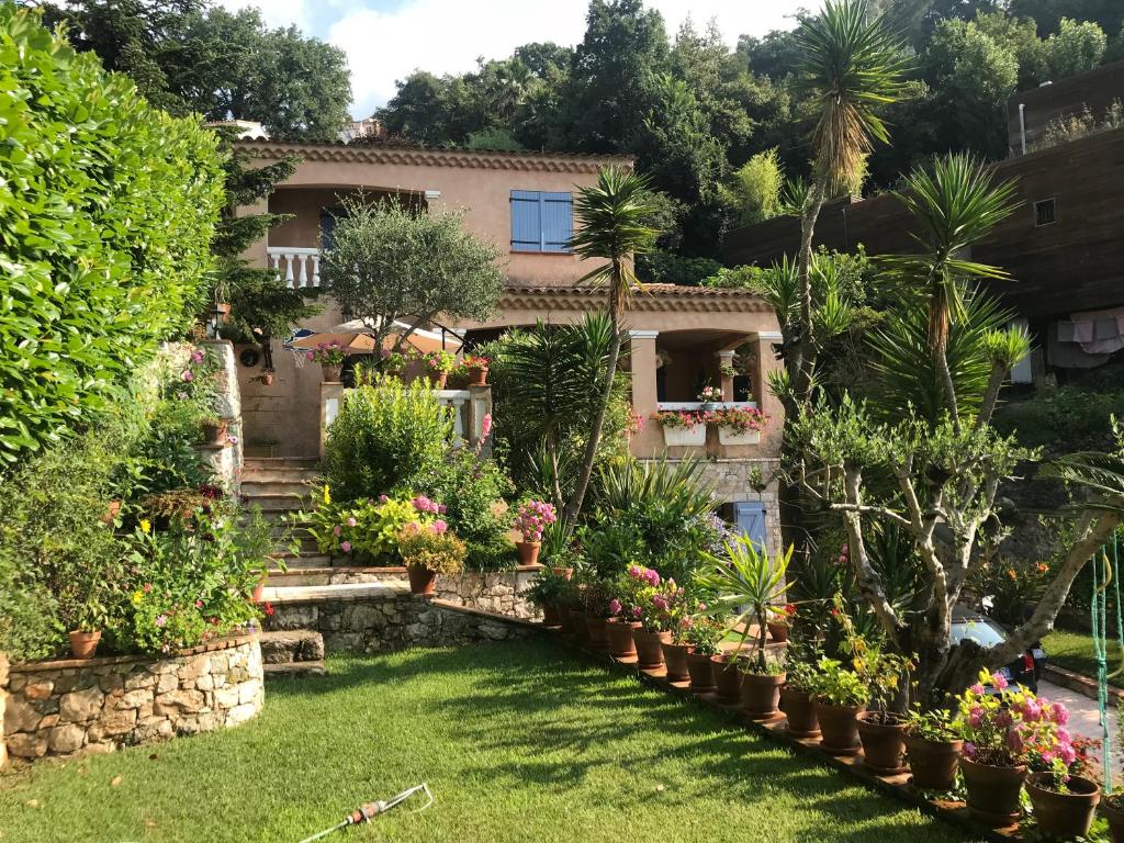 un jardin en face d'une maison ornée de plantes dans l'établissement Magnifique villa vue mer avec jacuzzi, à La Turbie