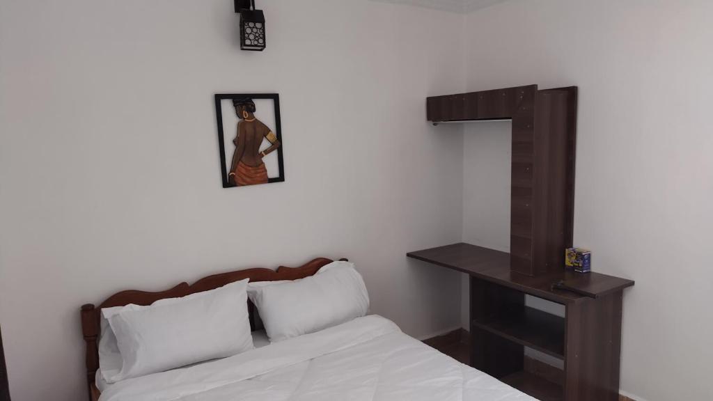 ein Schlafzimmer mit einem Bett und einem Kreuz an der Wand in der Unterkunft Precious Home stays in Maragoli