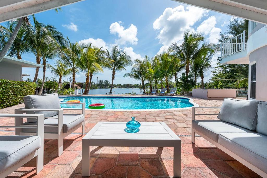 un patio con sillas y una piscina con palmeras. en Tropical Waterfront Family Oasis - Amazing Location, en Miami