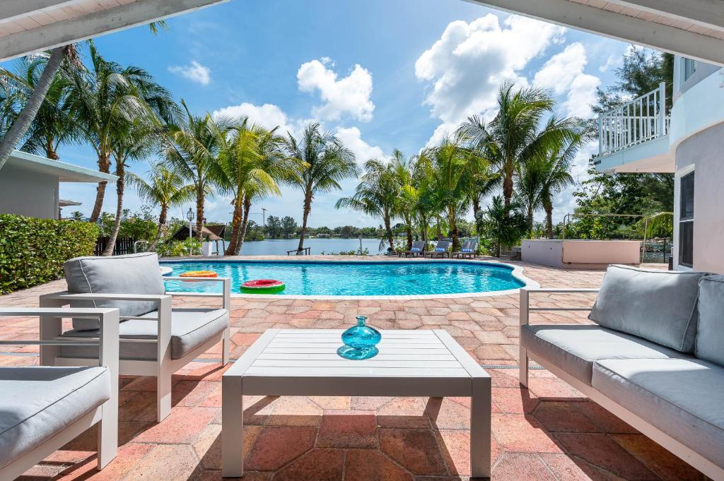 un patio con sedie e una piscina con palme di Tropical Waterfront Family Oasis - Amazing Location a Miami