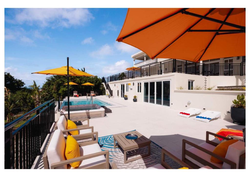 a patio with chairs and umbrellas next to a pool at Sauna Pool Game Room Bliss in Rodney Bay Village