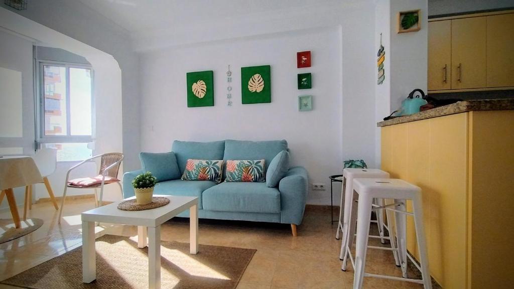 a living room with a blue couch and a table at Hoja Calá Apartment in Algarrobo-Costa