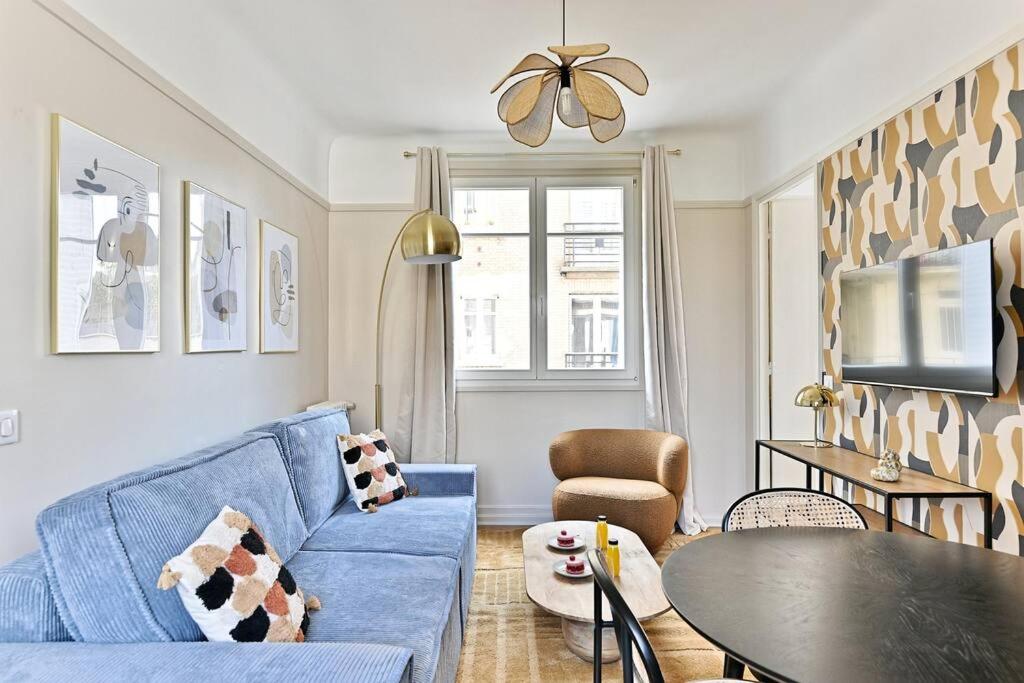 un salon avec un canapé bleu et une table dans l'établissement Appartement moderne et coloré Neuilly-sur-Seine, à Neuilly-sur-Seine