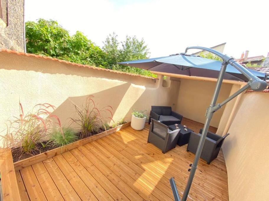 eine Terrasse mit einem Sonnenschirm, einem Tisch und Stühlen in der Unterkunft Terrasse en Ville A 10 min Gare SNCF et 30 min de LYON in Rive-de-Gier