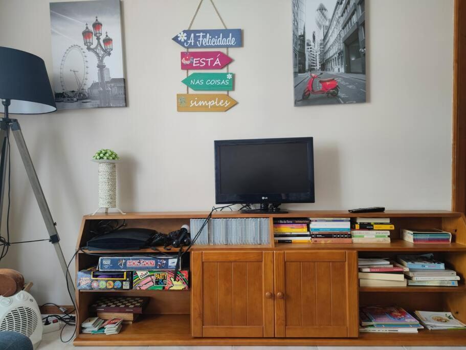 TV en un centro de entretenimiento de madera con libros en Brisa do Mar, en Vagos