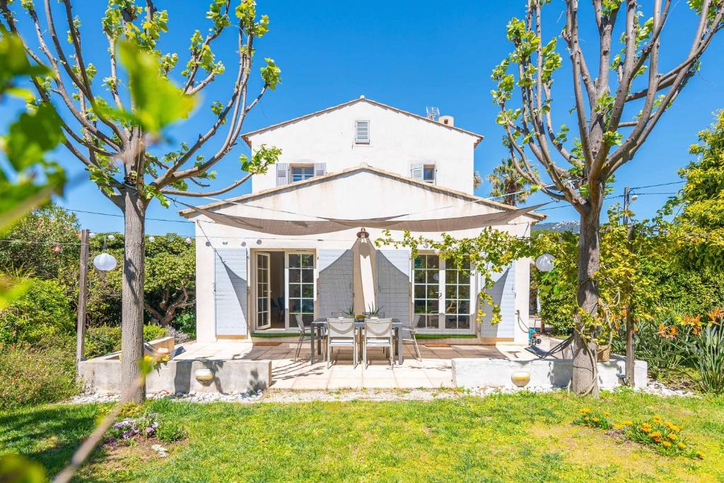 ein weißes Haus mit einem Tisch und Stühlen im Hof in der Unterkunft Maison Cap Brun Jardin Parking in Toulon