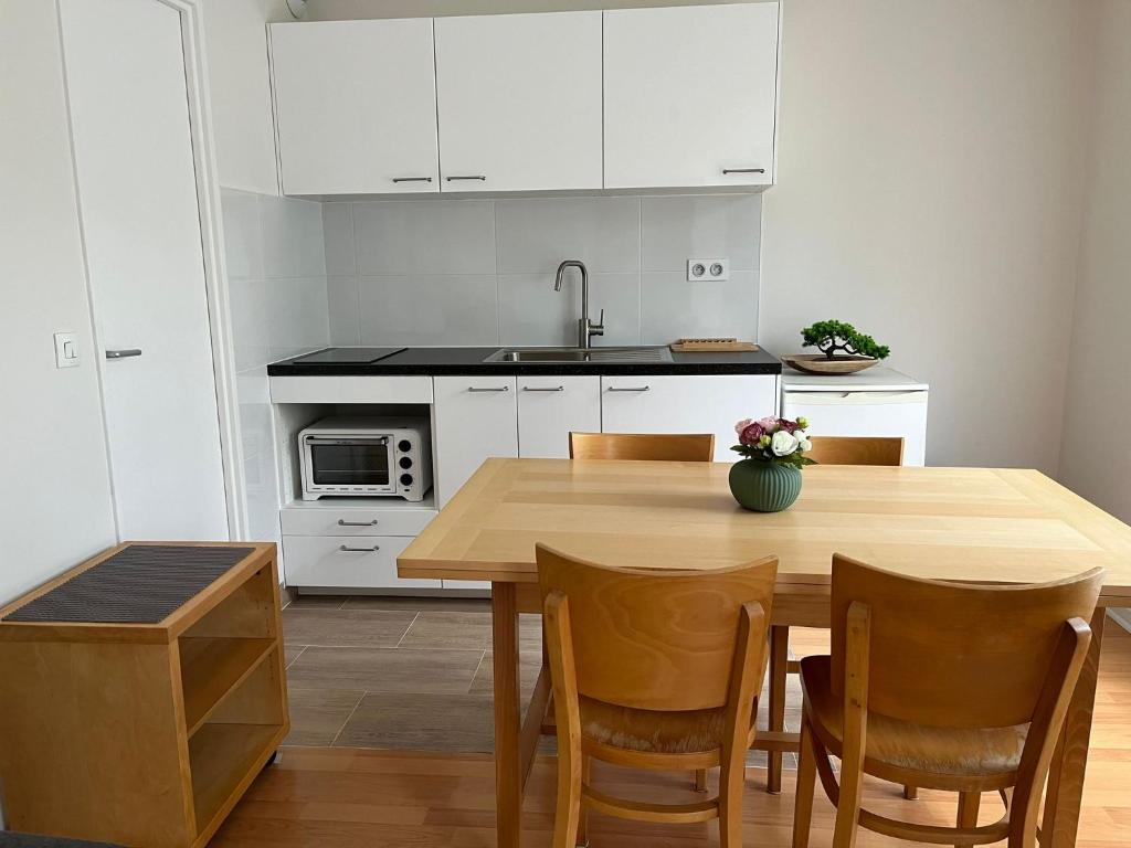 a kitchen with a wooden table and white cabinets at Studio rénové avril 2024 wifi et parking in Le Port-Marly