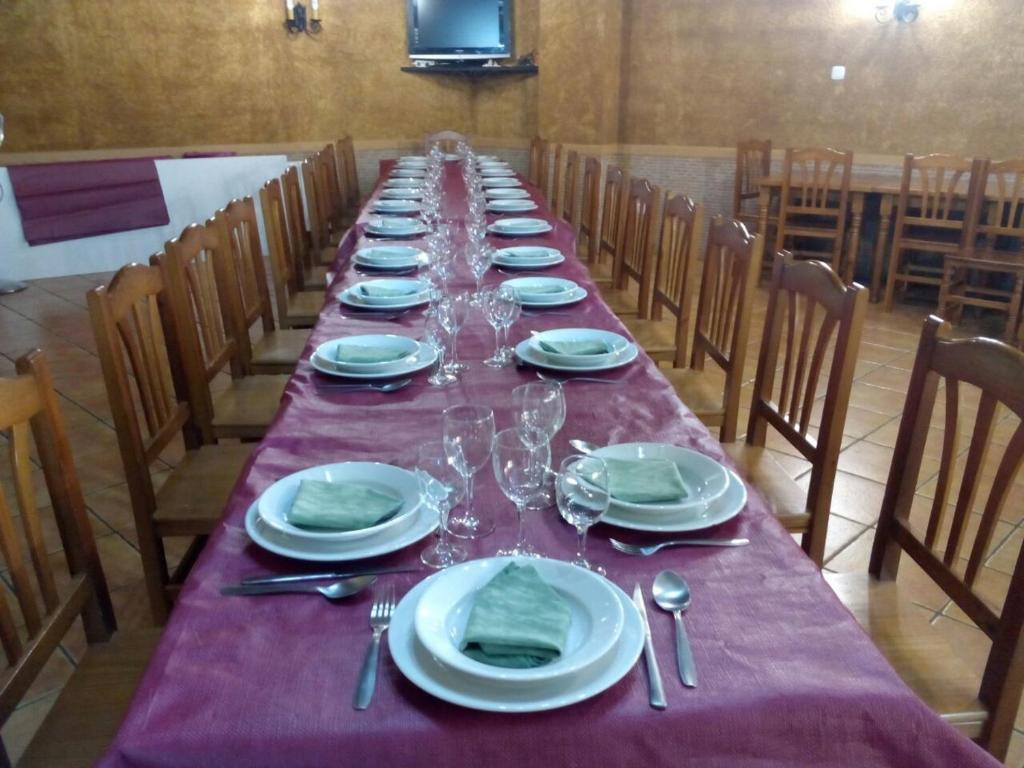 una mesa larga con platos y copas de vino. en Pensión El abuelo, en Carbellino