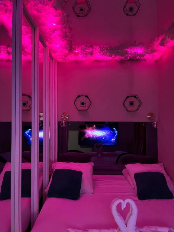 une chambre rose avec un lit aux lumières roses dans l'établissement Le BLUE, à Aubervilliers