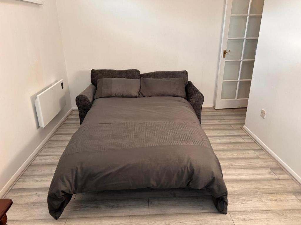 a bed in a white room with a couch at Stunning one bed Apartment with free Wifi and Parking in Goodmayes