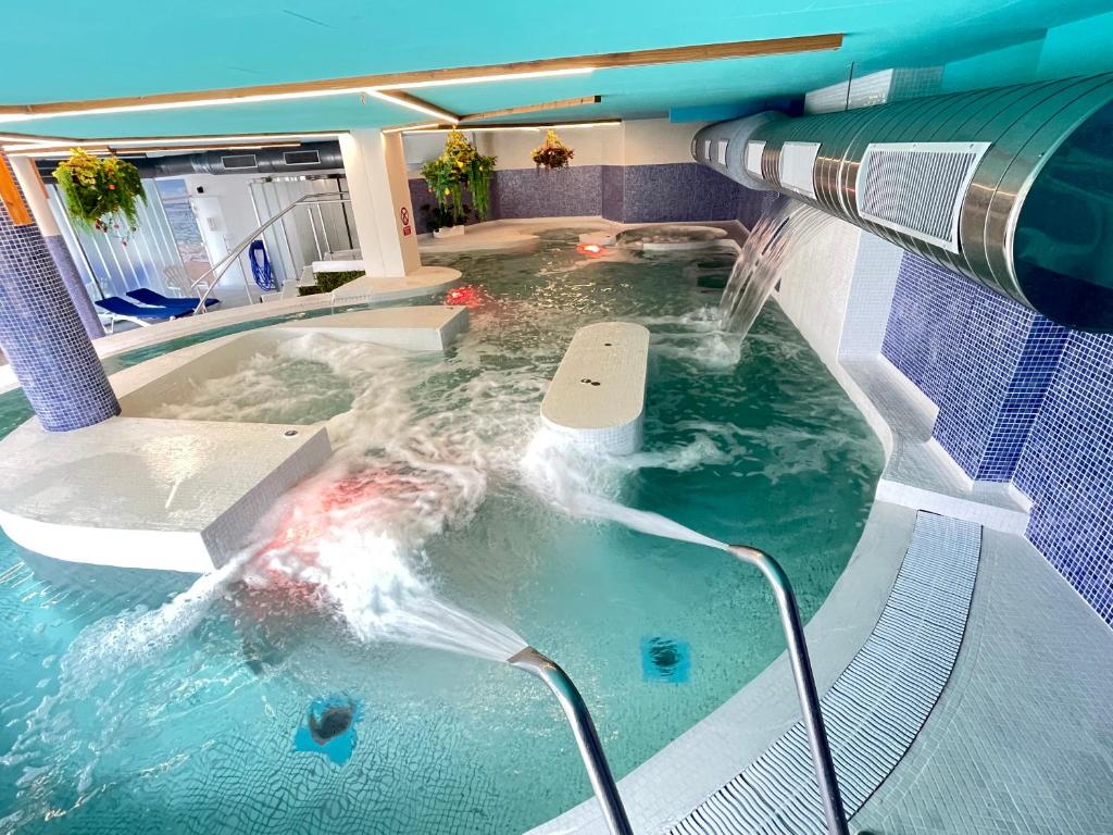 a swimming pool with a water fountain in it at Hotel Spa Playa Langosteira by Adeloló in Finisterre