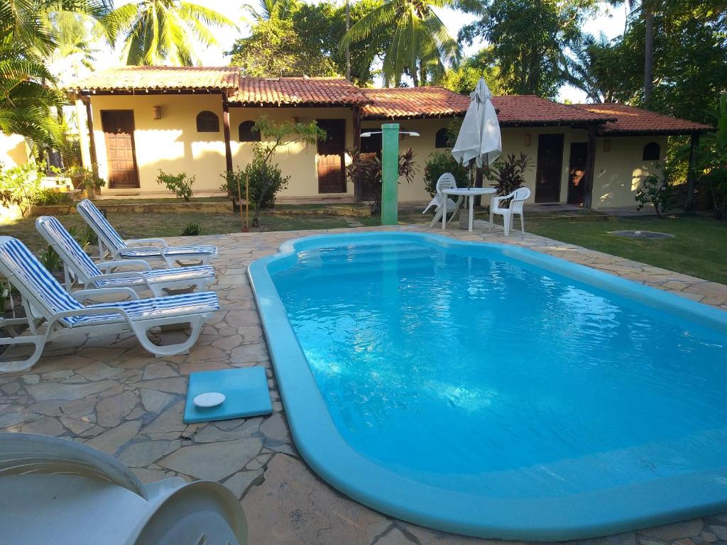 a swimming pool with chairs and a house at Pousada Vila Imbassai in Imbassai
