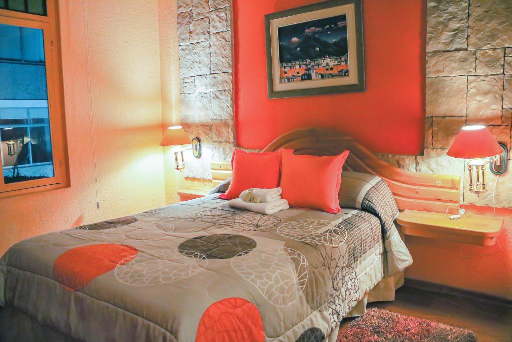 a bedroom with a large bed with orange walls at Hotel Rodelu in Latacunga