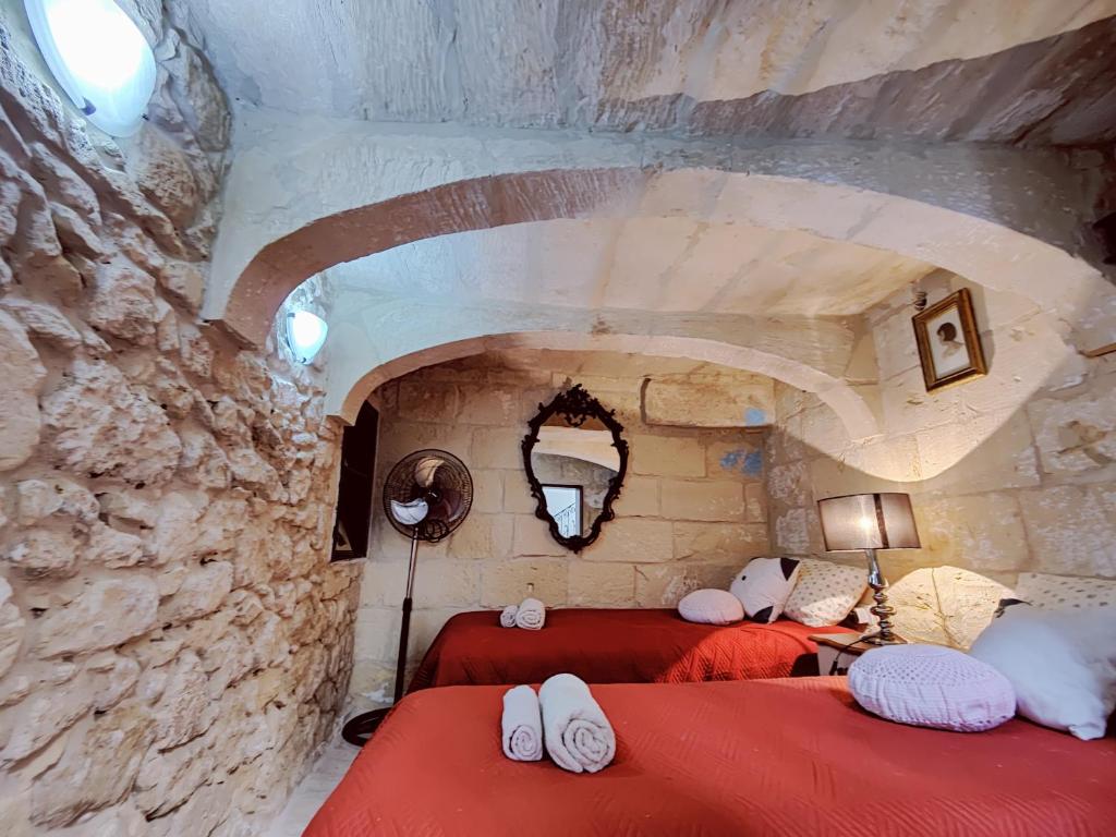 1 dormitorio con 2 camas rojas en una pared de piedra en Traditional Maltese Townhouse in Rabat, en Rabat