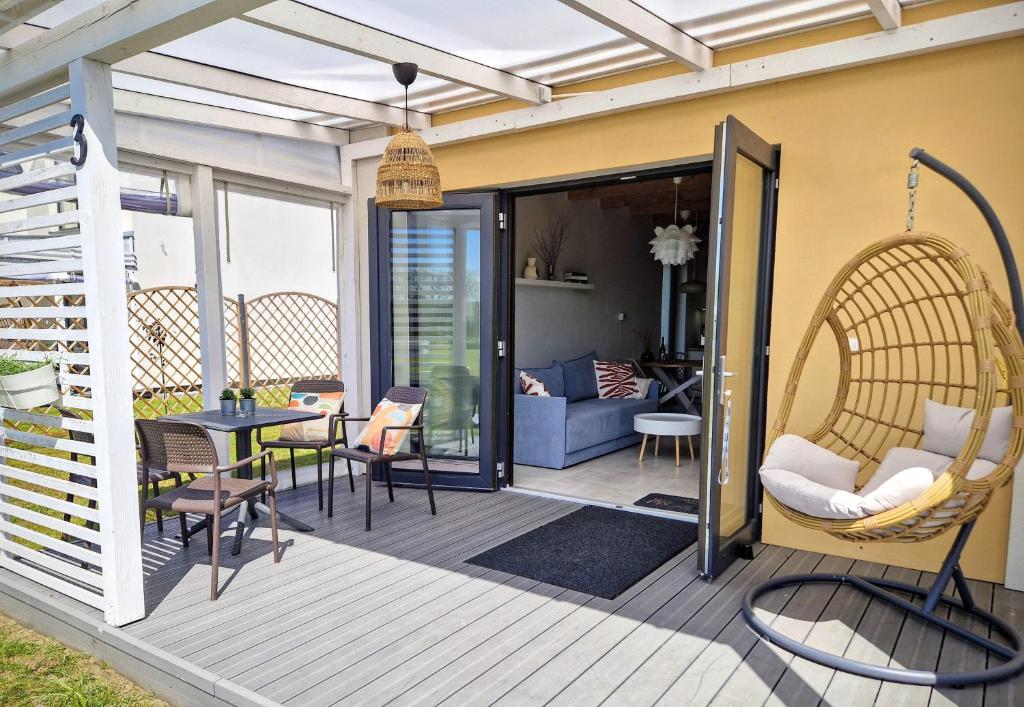 Una terraza con una silla de mimbre y una mesa. en Domki Całoroczne nad Morzem Kraina Bałtyku, en Przewłoka