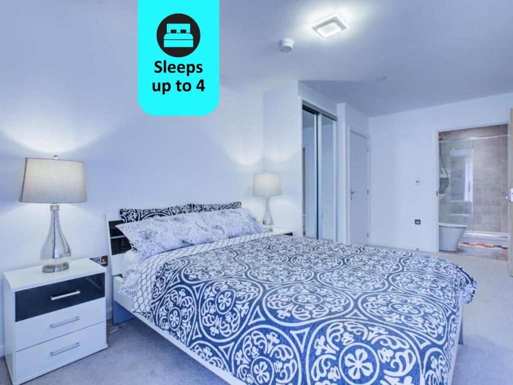 a bedroom with a bed with a blue and white comforter at 2 bed 2 bath Modern Apartment in East Acton in London