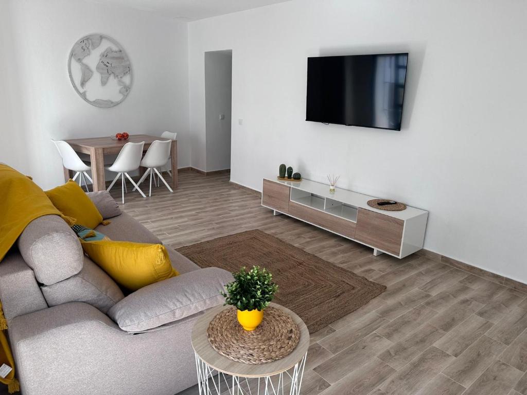 sala de estar con sofá y TV en la pared en Solera, en Jerez de la Frontera