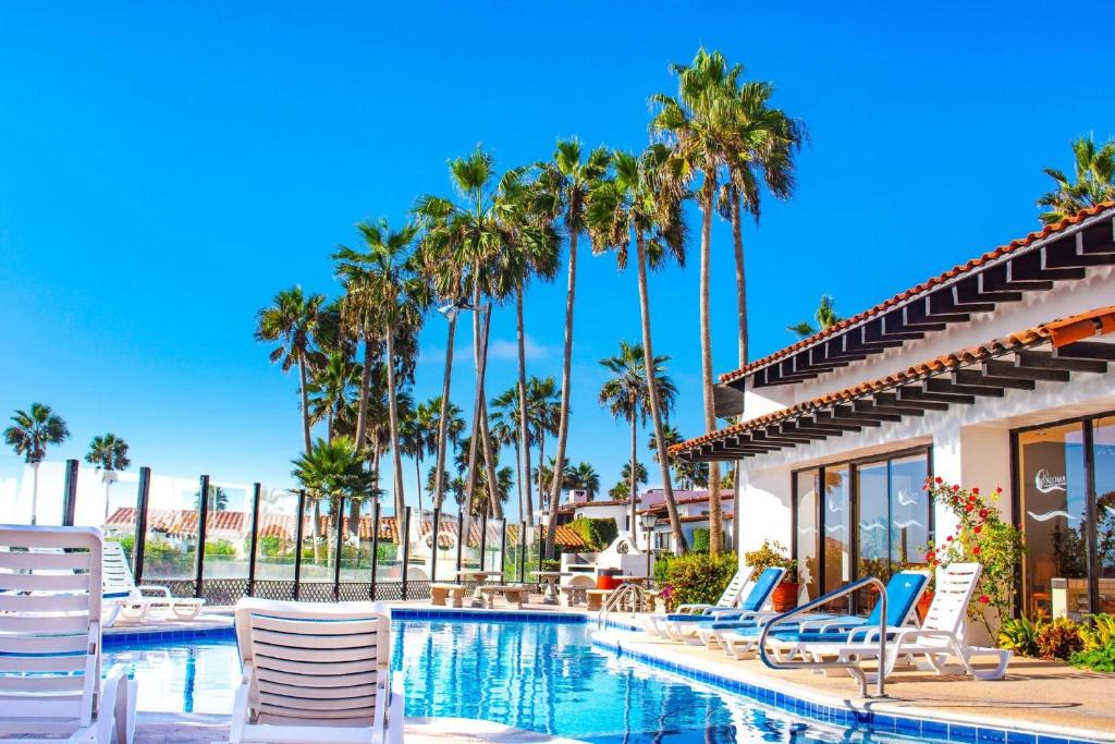 uma piscina num resort com cadeiras e palmeiras em WIVC La Paloma Resort - Your Vacation Escape to Rosarito, Swimming Pool & Short Walk To The Beach em Popotla