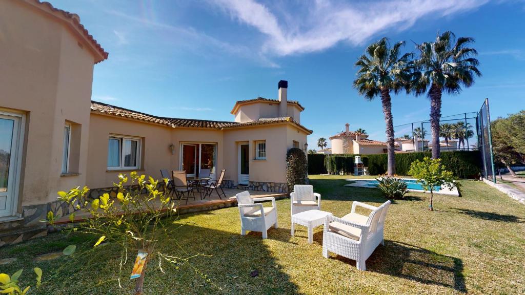 una casa con un patio con sillas blancas y palmeras en Villa Boreal by ON Travel, en Oliva