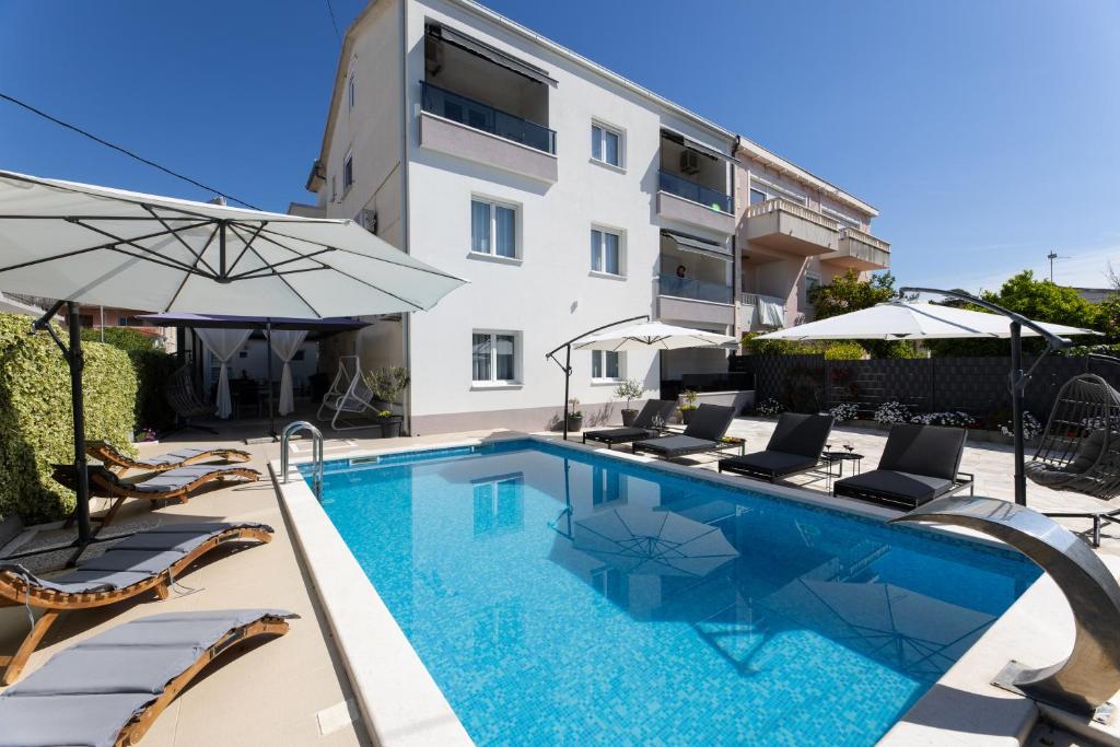カシュテラにあるModerni studioの建物の隣にスイミングプール(椅子、パラソル付)