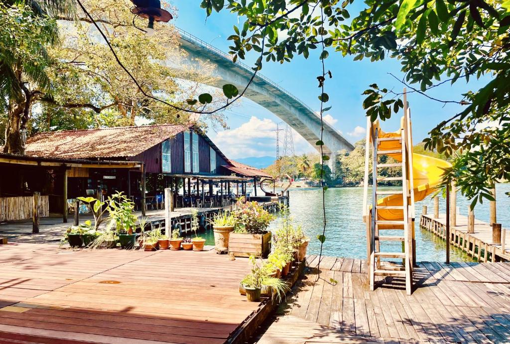 a wooden dock with plants on it next to the water at HOTEL BACKPACKERS RIO DULCE in Rio Dulce