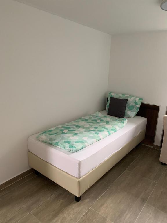 Cama pequeña en habitación con pared blanca en Ferienunterkunft Zeitwohnen, en Wilhelmshaven