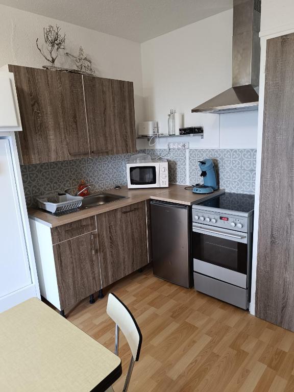 - une cuisine avec des placards en bois et un four micro-ondes blanc dans l'établissement Studio agréable tout confort, aux Angles