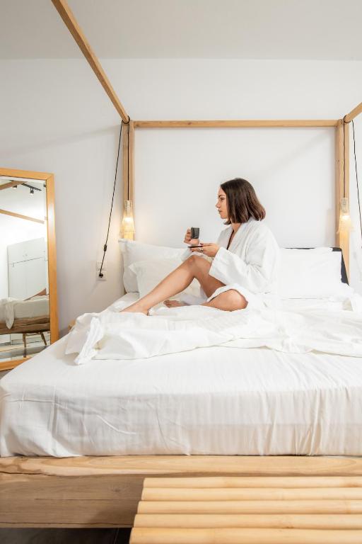 a woman sitting on top of a bed at Casa Naturale in Skopelos Town