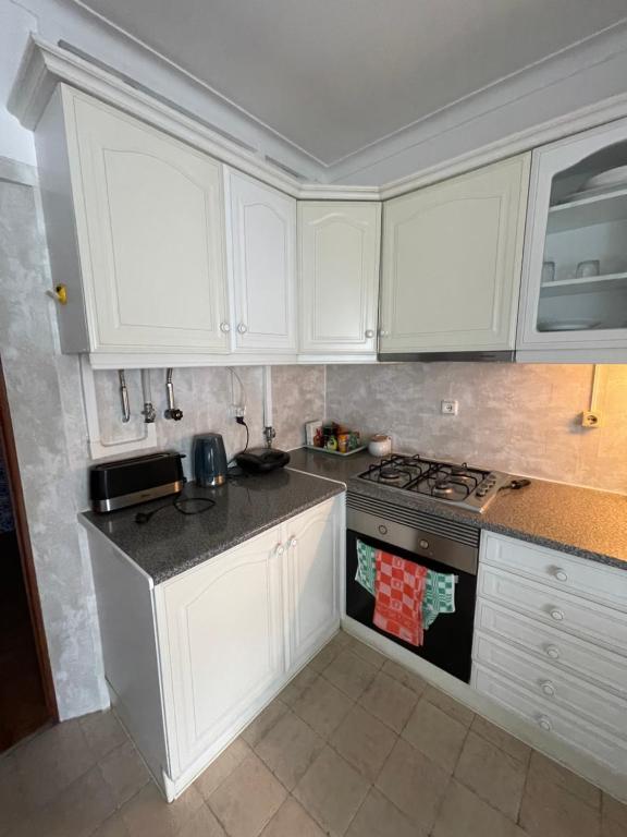 uma cozinha com armários brancos e um fogão em Quarto de Casal Acolhedor em Laranjeira