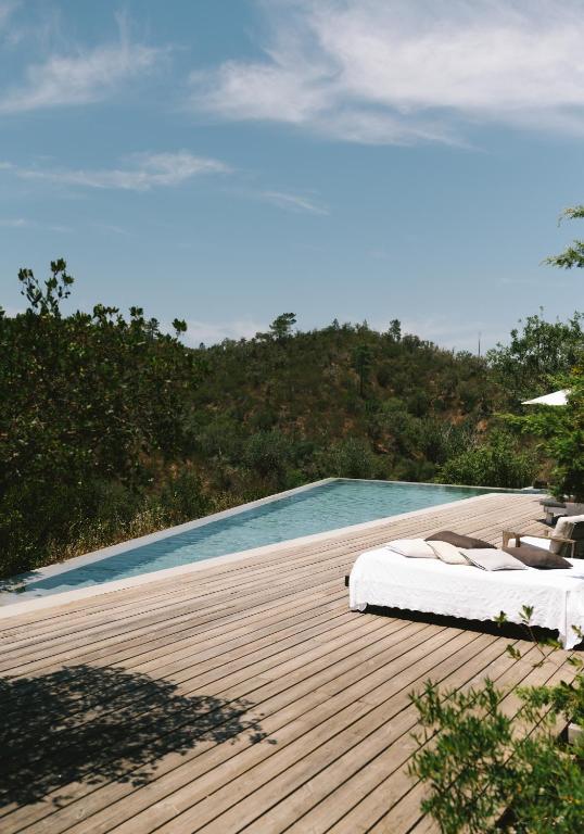a bed on a wooden deck next to a swimming pool at The ONE - Country House in Grândola
