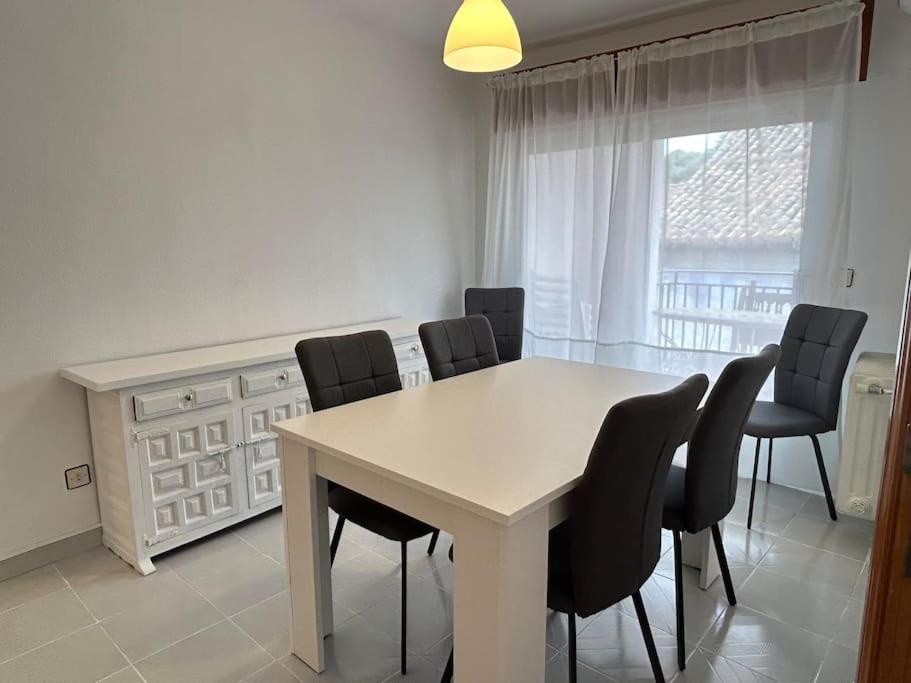 une salle à manger avec une table et des chaises blanches dans l'établissement Calle Larga 43/2, à La Adrada