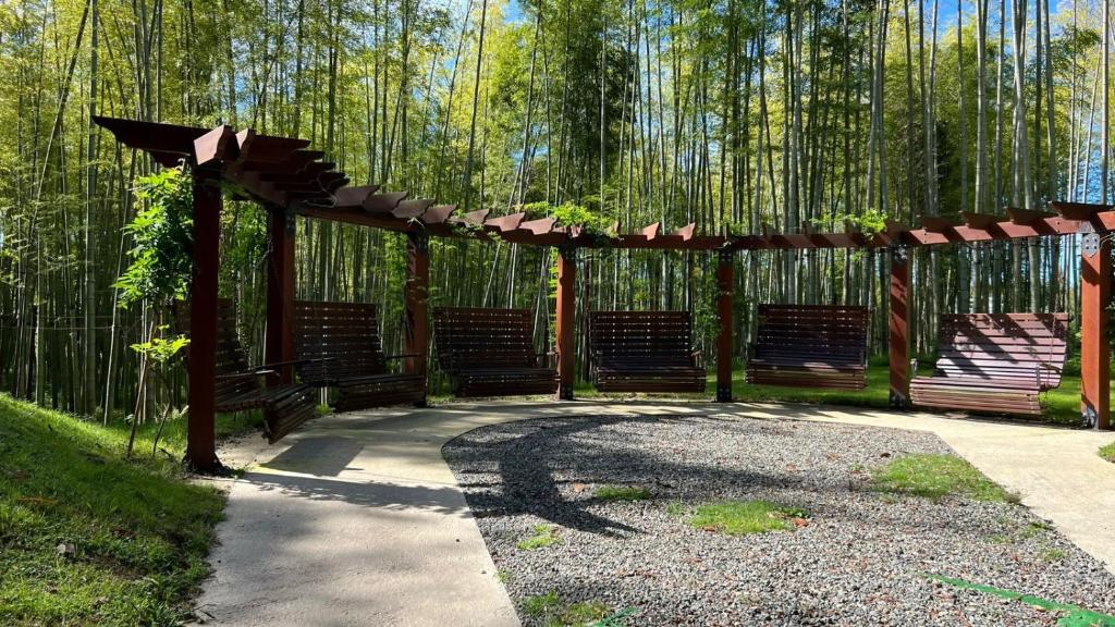 a wooden pergola with benches in a park at Femyli rooms in Shekvetili