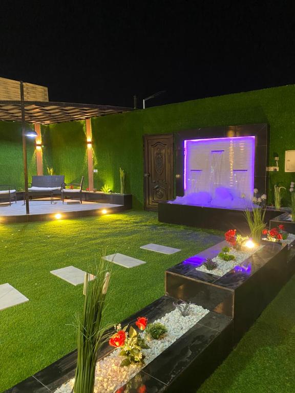 un giardino di notte con un grande schermo di شاليهات لانا لاند نموذج 1 a As Sayl aş Şaghīr