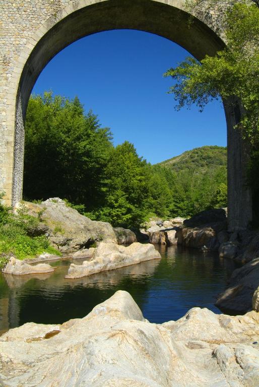 un pont sur une rivière avec des rochers et des arbres dans l'établissement Gîtes de Neyrac, appartement Rose - piscine, rivière à 100 m, vue sur les collines, à Meyras